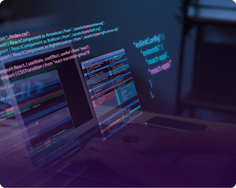 Dual computer monitors displaying colorful React source code lines and configuration files in a dark room