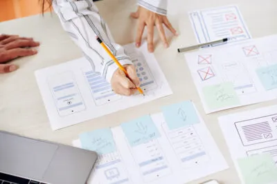 Person drawing user flow sketches and wireframes on paper with a pencil
