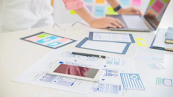 Digital tablet and paper UI wireframes on a desk