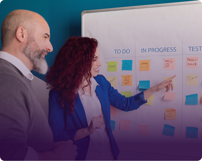 Two team members pointing at colorful sticky notes on an Agile Scrum board during a planning session