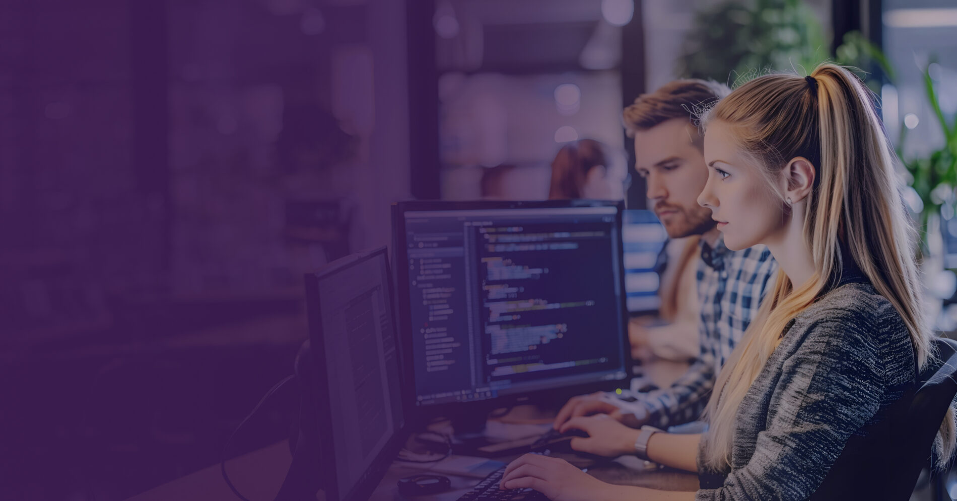 Male and female developers reviewing code on monitors