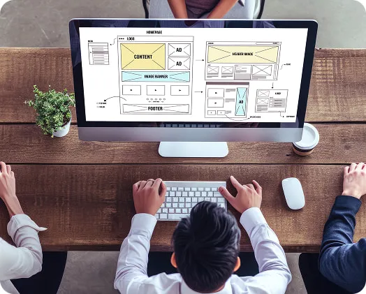 Designers collaborating on website layout wireframes on a desktop screen