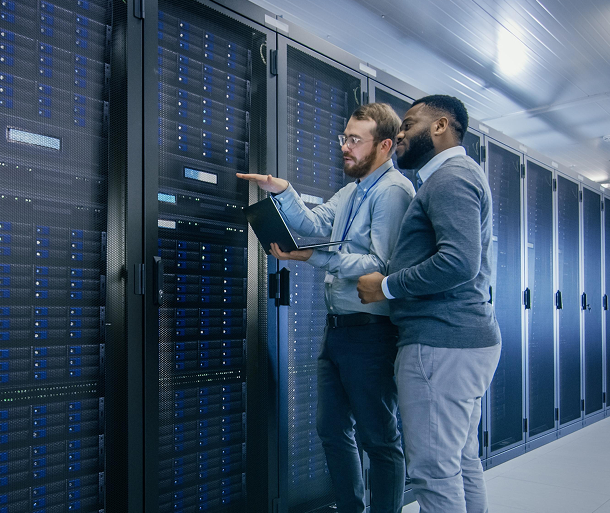 Two men in a data center reviewing rows of server racks